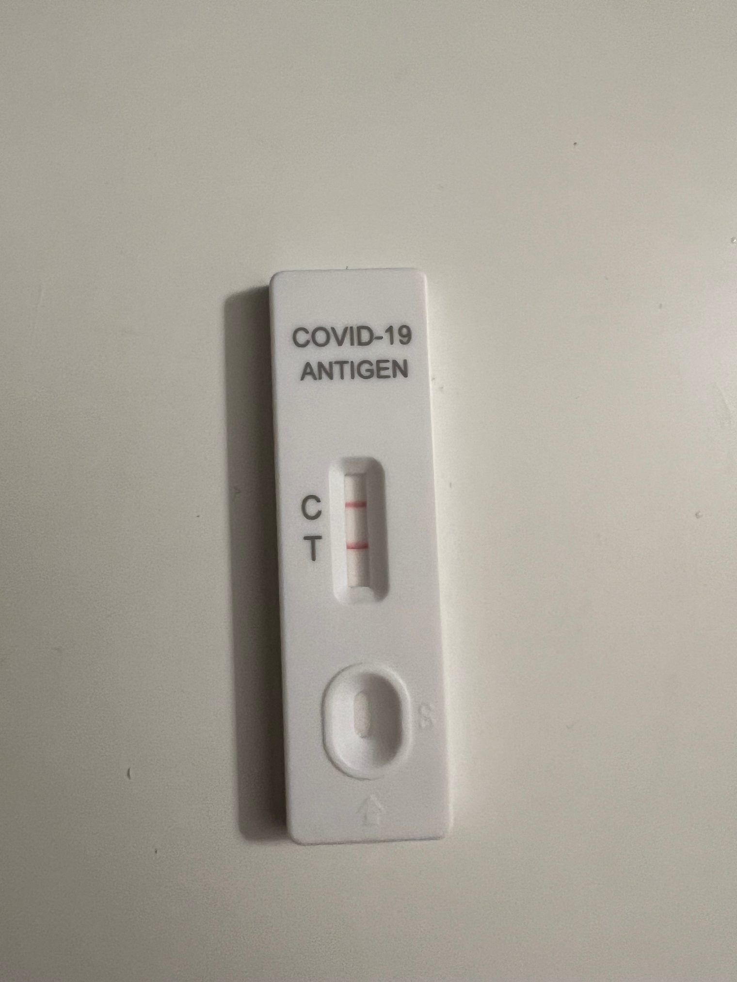 A COVID-19 rapid antigen test with two red lines at C and T: positive