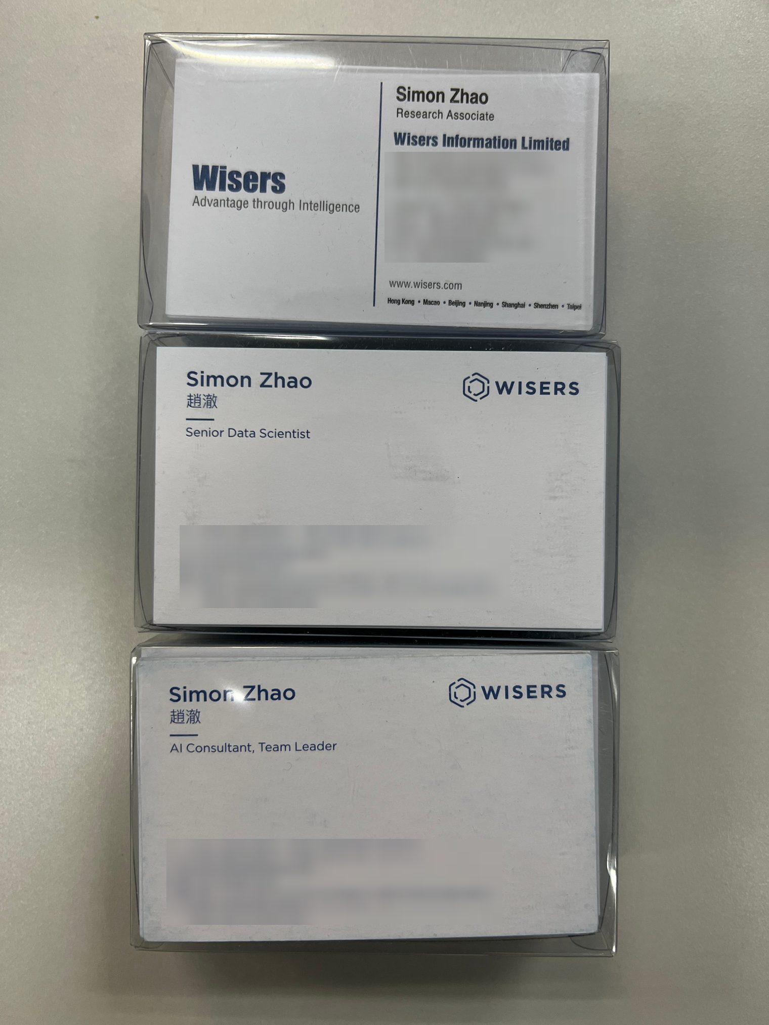 Three stacked boxes of business cards from the same company, each with a different job title