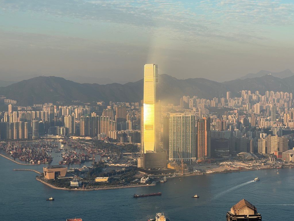 From high above, the setting sun turns the International Commerce Centre gold, with the West Kowloon waterfront and a typhoon shelter in front