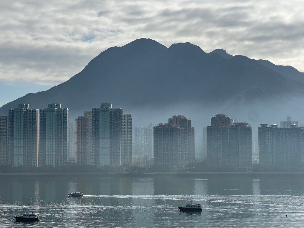 Ma On Shan and the tower blocks in morning haze, three small boats crossing the water