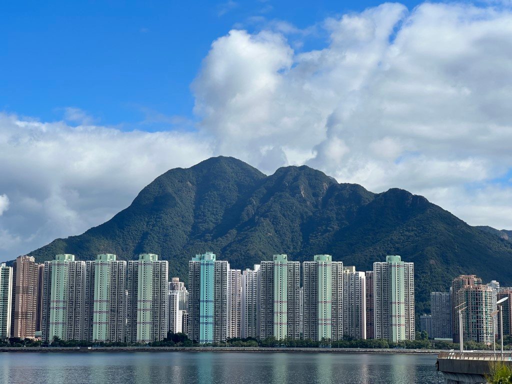 Ma On Shan on a clear day across Tolo Harbour, a row of tower blocks at its foot and white clouds piled up behind