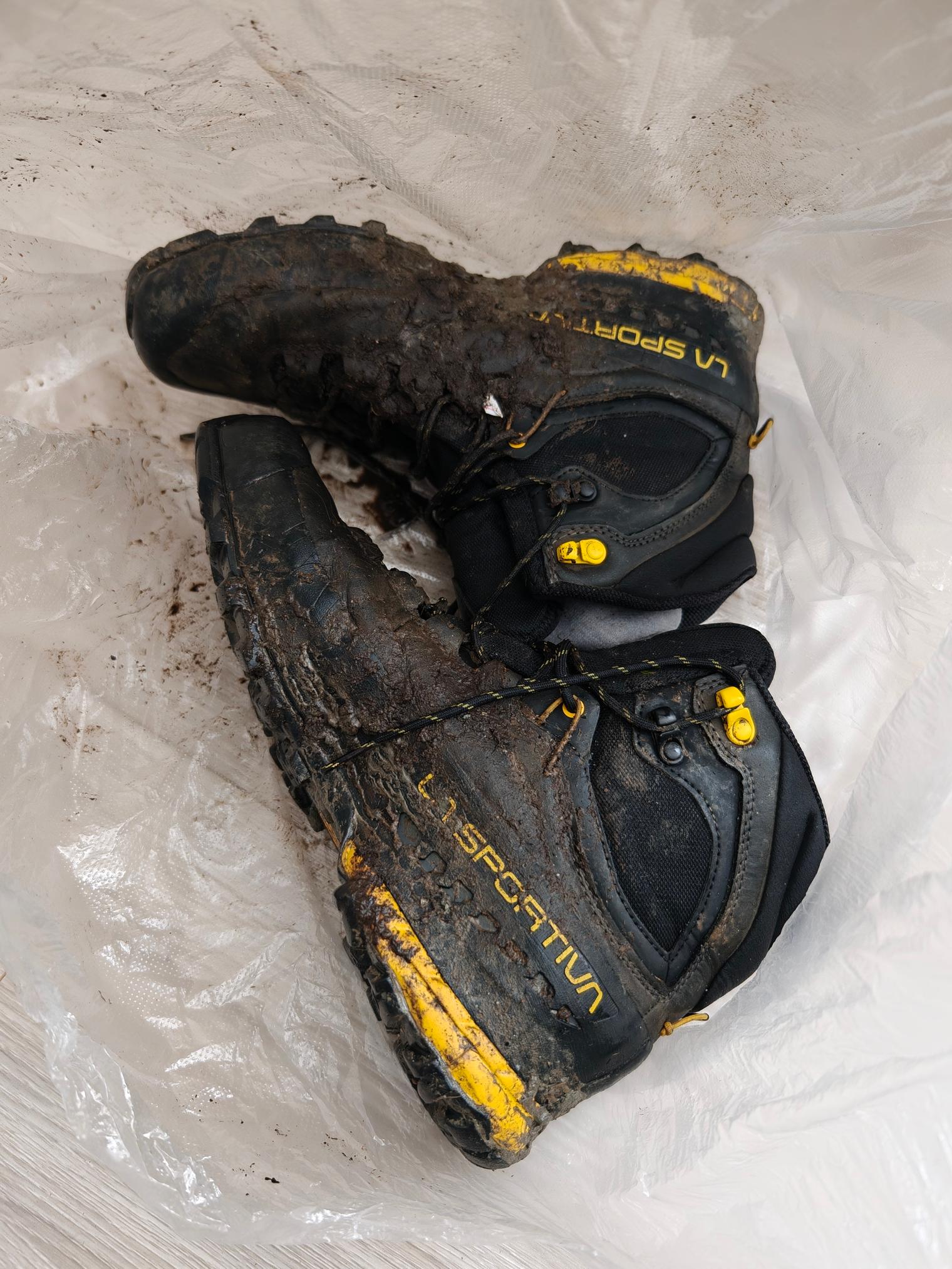 Mud-caked mountaineering boots set down on a plastic sheet