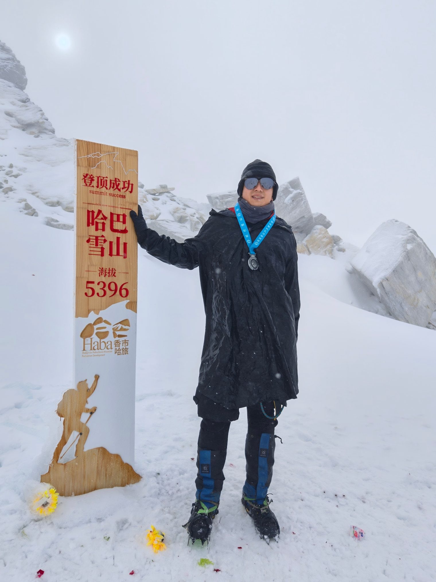 The author with a summit medal, standing beside the 5396 m marker in crampons