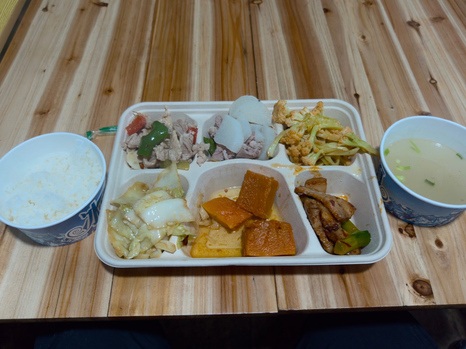 A compartment tray of canteen food with a bowl of rice and a bowl of soup