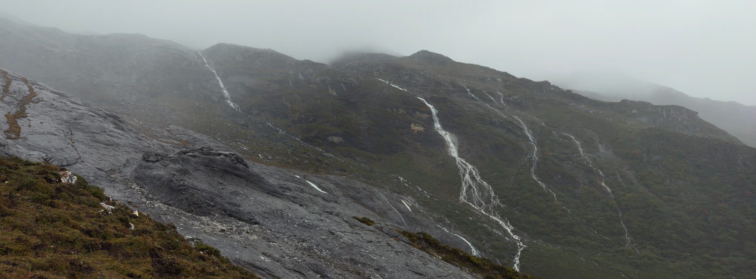 Meltwater streaming down grey rock slabs on a misty mountainside