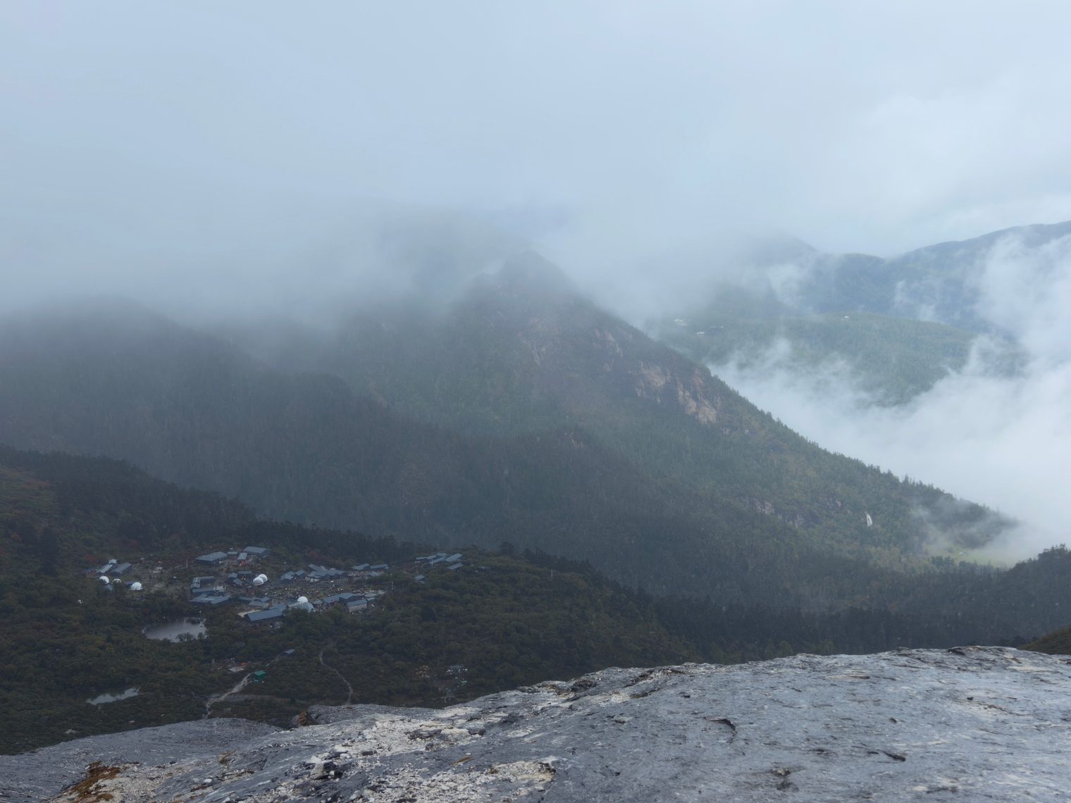 Looking down from a rock ledge at the village and valley below the clouds
