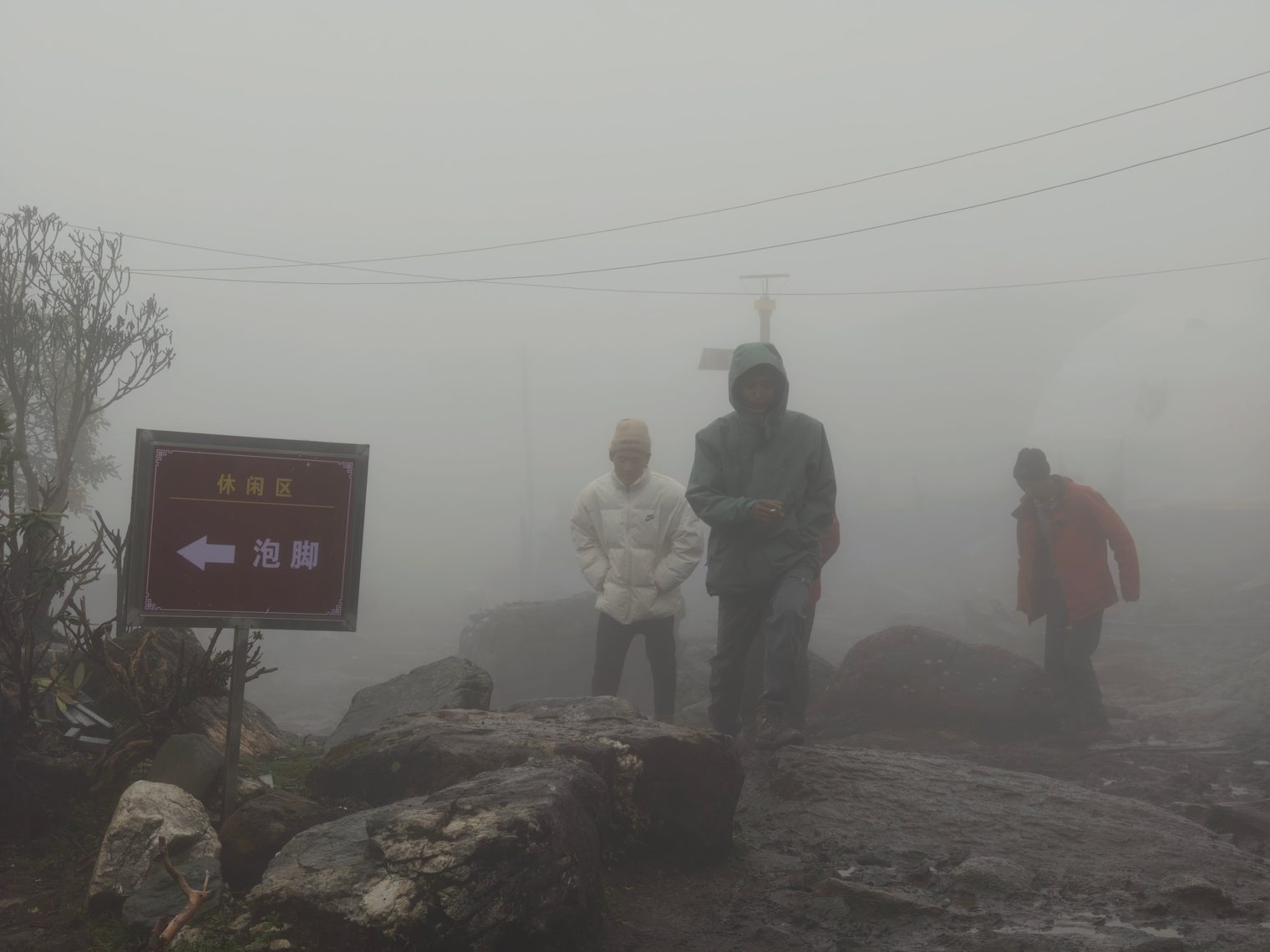 Three people in down jackets beside a sign pointing to the foot-soak area